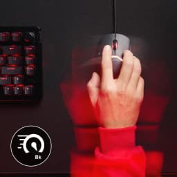 Souris Gaming HyperX Pulsefire Saga 3200 DPI RGB Noir, en utilisation: main en manche rouge la tenant sur bureau sombre près