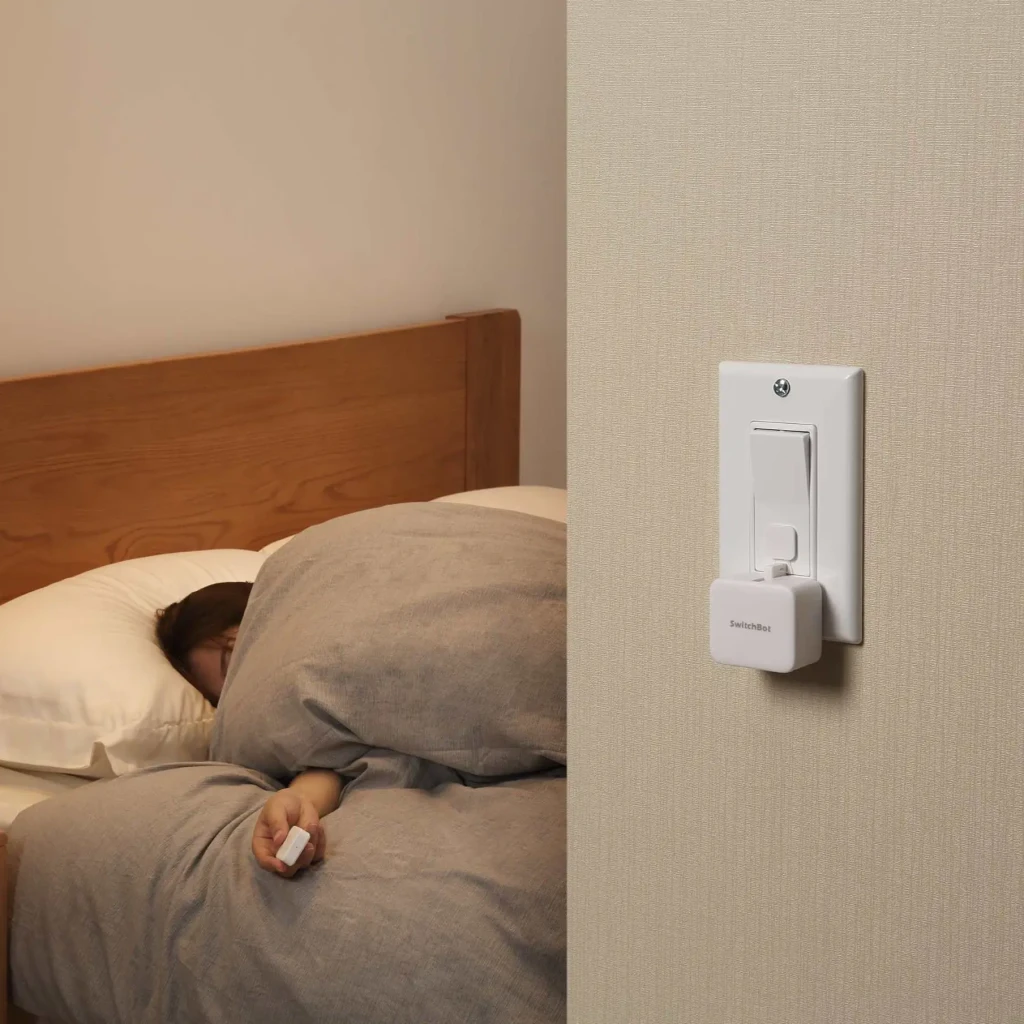 Mando a distancia inteligente SwitchBot Remote W0301700 Bluetooth 5.0, uso en dormitorio: persona en cama sostiene el mando