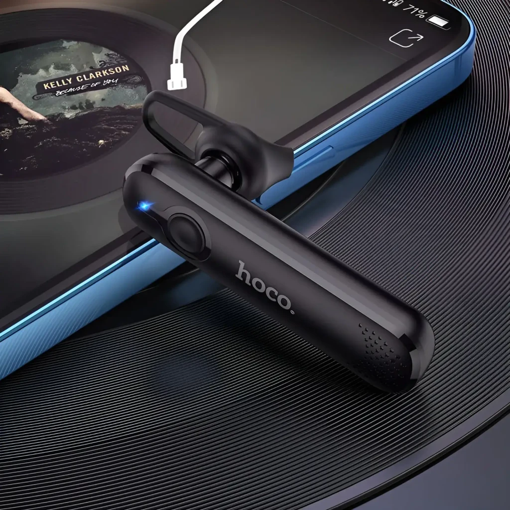 Auricular HOCO E63 Diamond In-Ear Mono Bluetooth 5.0 6h, en uso: negro sobre disco de vinilo junto a smartphone, LED azul