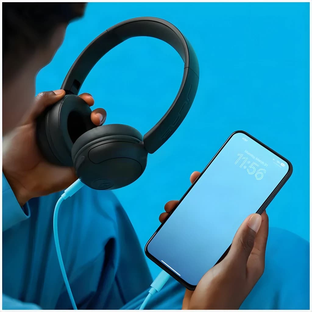 Auriculares JLab Audio Studio 2 Wireless Diadema On-Ear Bluetooth 5.4, en uso: mano sostiene auriculares negros con cable