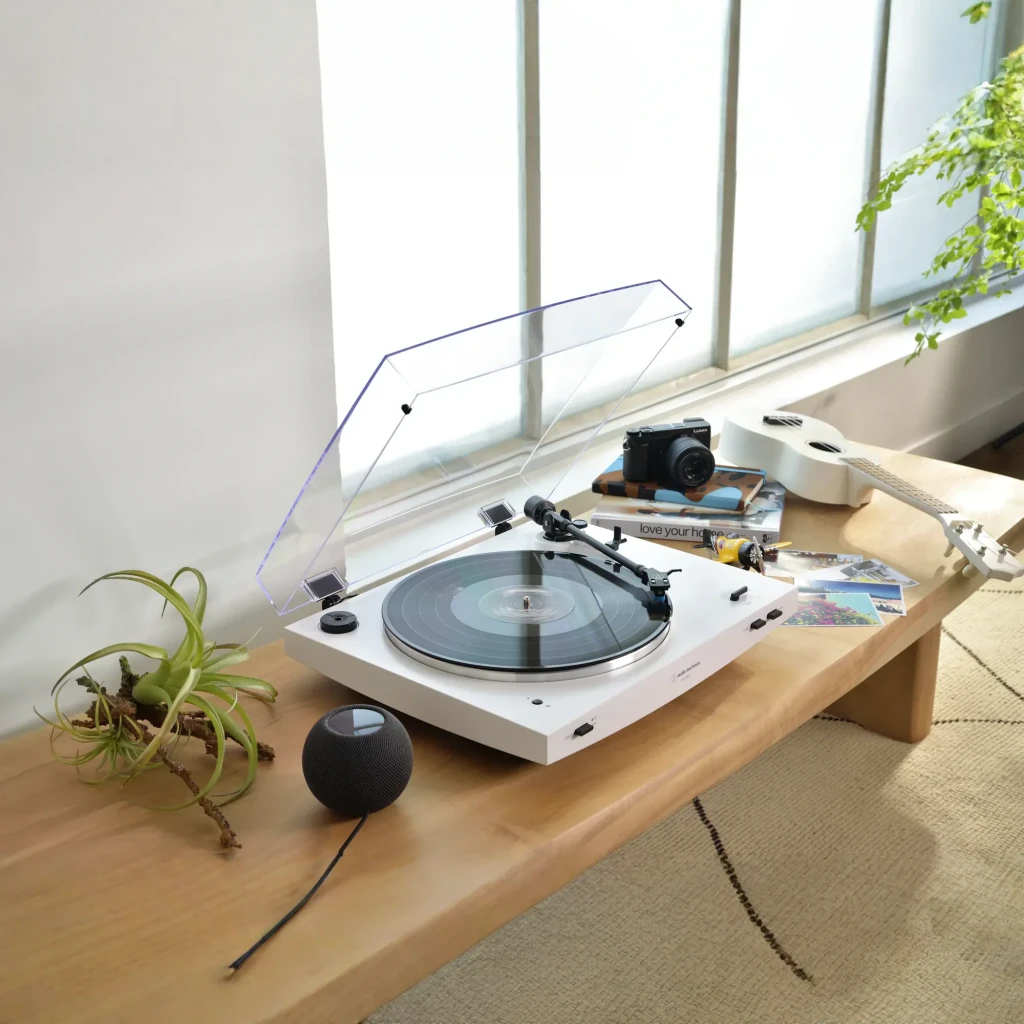 Platine vinyle Audio-Technica AT-LP3XBTWH Bluetooth 5.2, en situation: couvercle acrylique ouvert sur table en bois