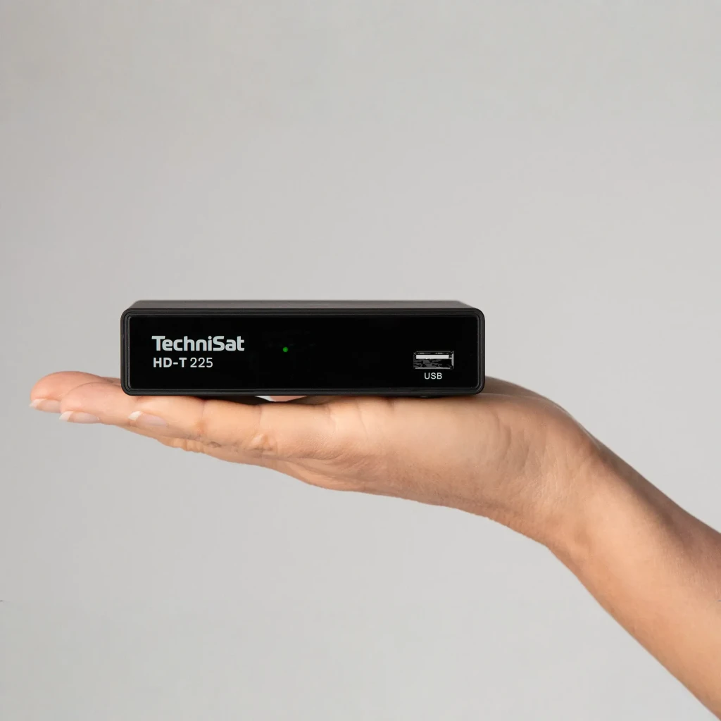 Receptor TechniSat DIGIT HD-T 225 HD TDT DVB-T2 HDMI USB en uso: mano sostiene el compacto receptor negro, frontal con logo