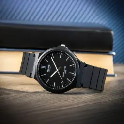 Casio MW-240-1EVDF Batterie 3 Ans 5ATM noir, en utilisation: montre sur bureau en bois près de livres, cadran noir