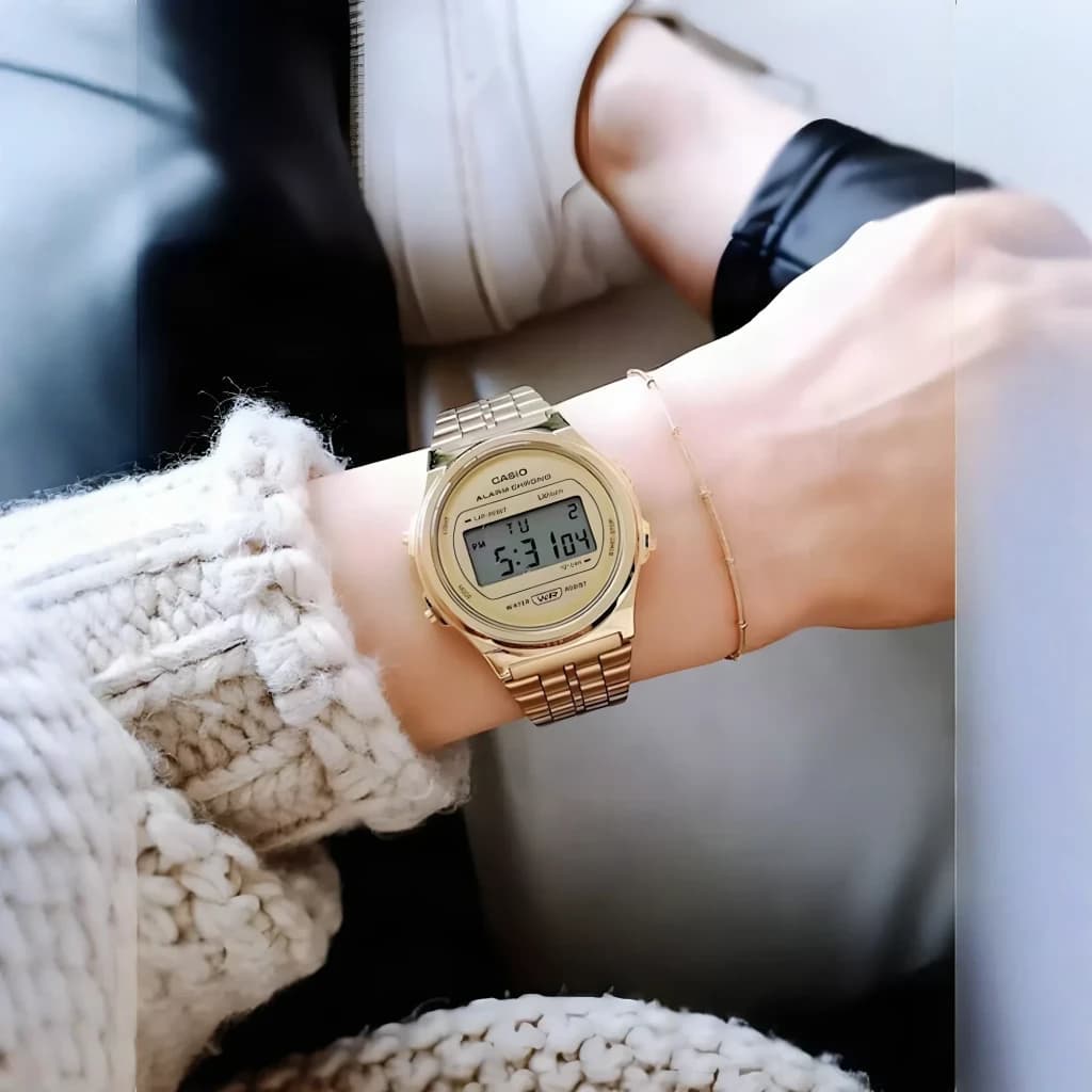 Casio Vintage A171WEG-9AEF Batterie 7 Ans Résistante à l'eau, en situation: montre dorée au poignet avec pull blanc