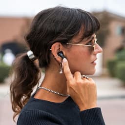 Auriculares JLab Audio Epic Pods ANC Cancelación de Ruido TWS Bluetooth 60h en uso: mujer de perfil ajusta el auricular
