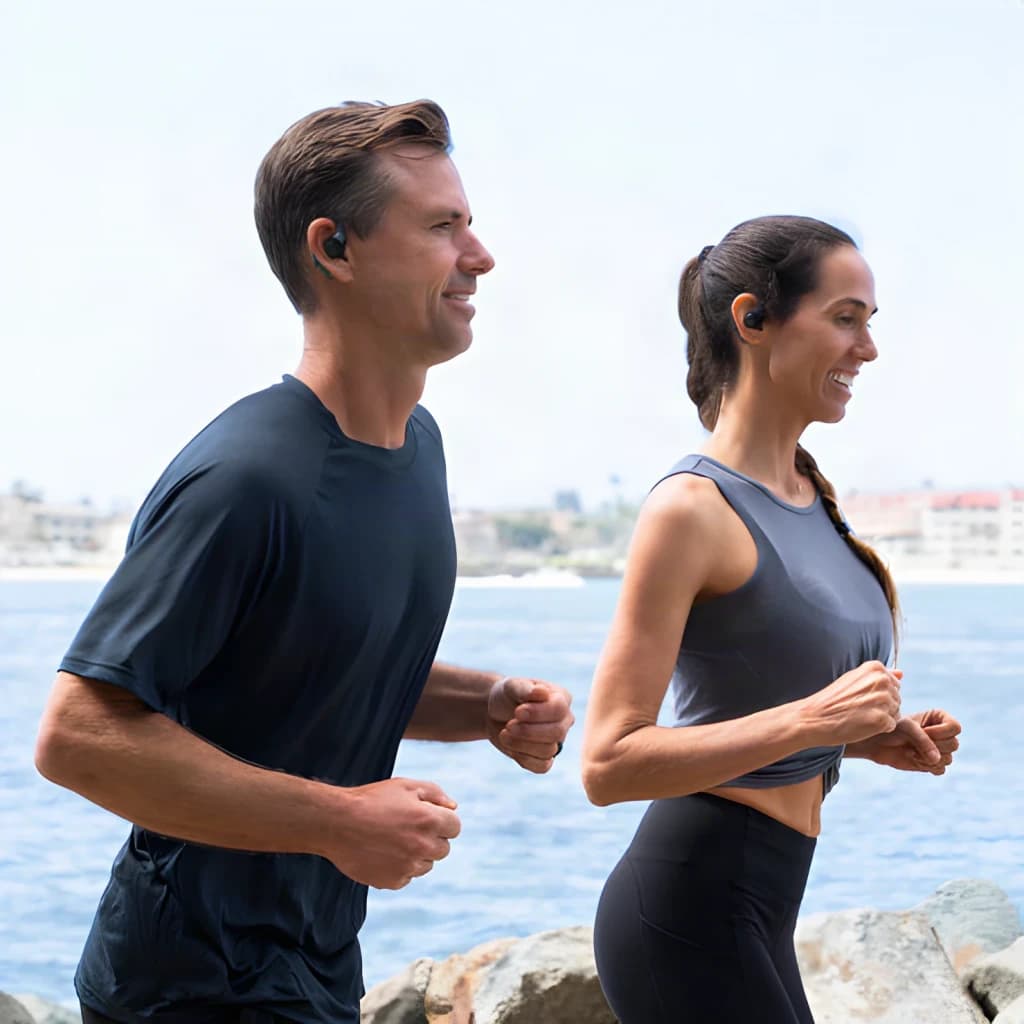 Auriculares JLab Audio Epic Open Sport Air Conduction Open-Ear TWS, uso: dos personas corriendo al aire libre junto al mar