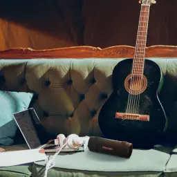 Altavoz portátil LG XBOOM Grab by will.i.am IP67 30W 20h Bluetooth 5.3, en uso: sobre sofá vintage junto a guitarra