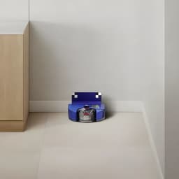 Robot aspirador Dyson 360 Vis Nav Sensor de infravermelhos 65min, vista lateral: robô azul a limpar junto ao rodapé e móvel