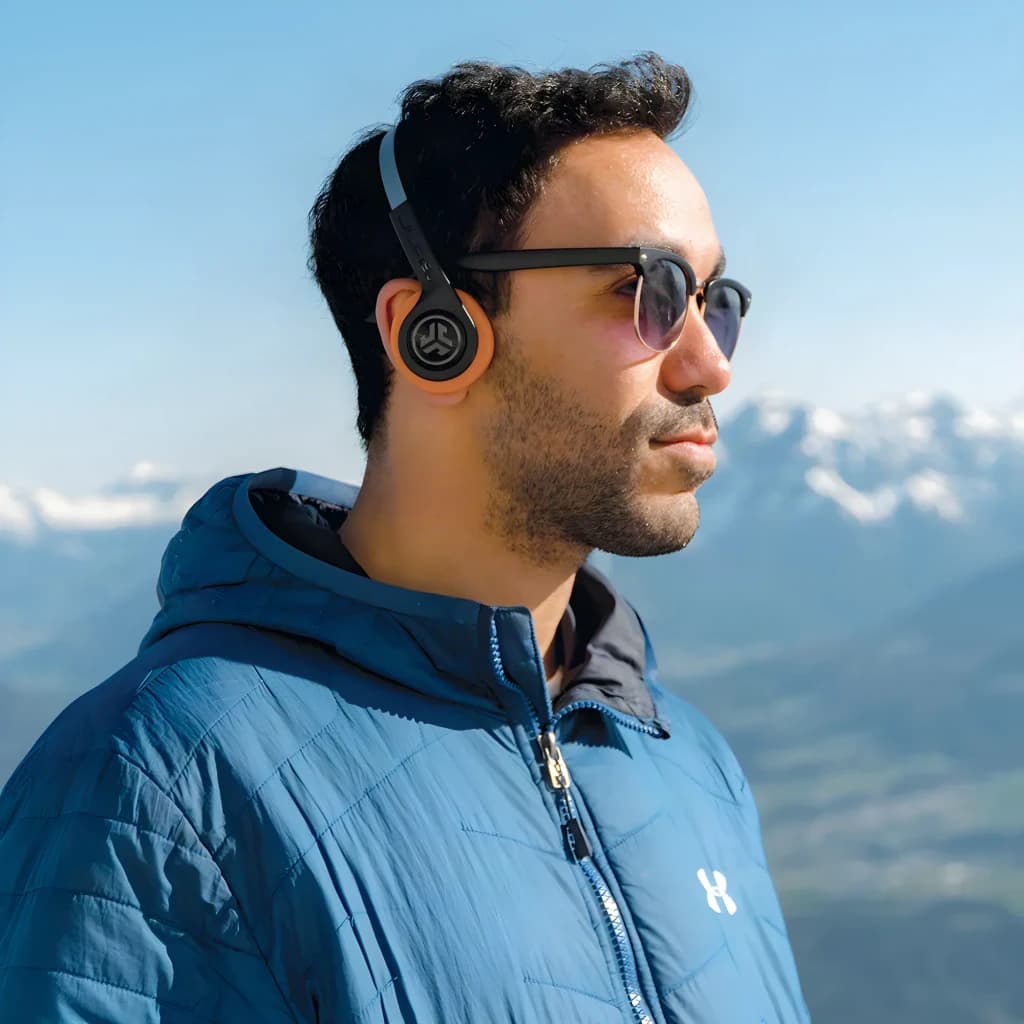 Auriculares JLab Audio Rewind 2 Diadema Bluetooth 5.0 20h puestos: hombre con gafas de sol en montaña, logo visible