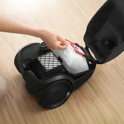 Aspirateur à sac Bosch Série 2 Noir 600W BGDS2CHAMP, en cours d'utilisation: main retirant le sac, couvercle ouvert