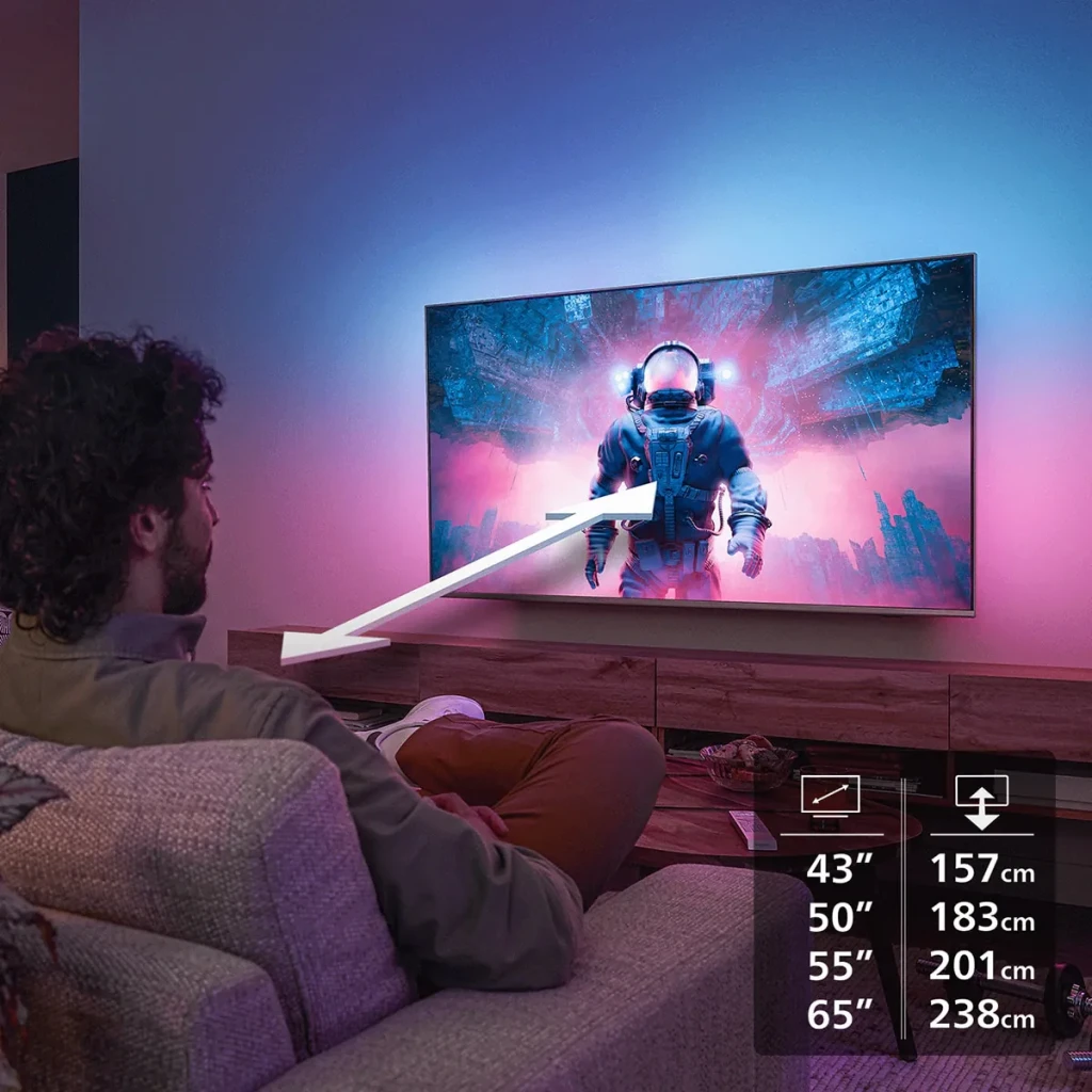 TV Philips 65 pouces LED 4K UHD Titan OS Noir 65PUS8001/12, scène: personne sur canapé regardant la TV avec Ambilight