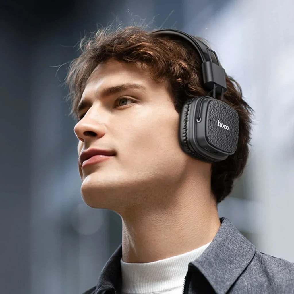 Auriculares Hoco W56 Earl Diadema Bluetooth 5.4 28h, en uso: hombre con auriculares negros over-ear, logo hoco visible