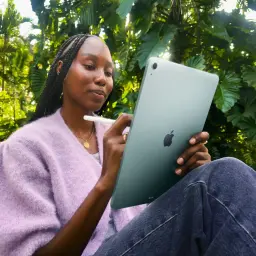 Apple iPad Air M4 13 pouces 128 Go Gris Sidéral 5G - femme tenant l'iPad avec Apple Pencil en extérieur, vue arrière