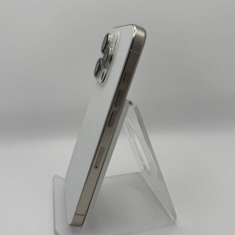 iPhone 15 Pro 5G 256Go Titane Blanc, état excellent: dos blanc mat, bords titane brossé, triple module photo pro, design fin posé sur support transparent.