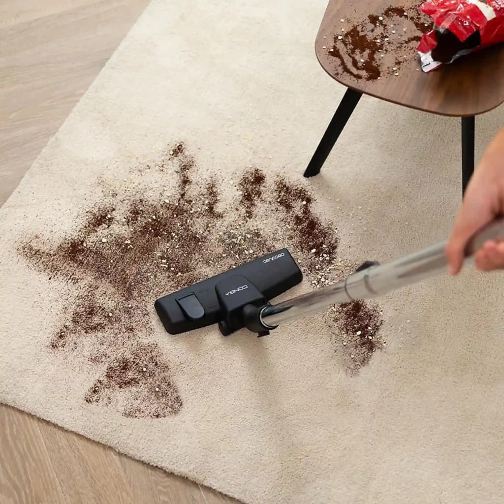 Cepillo del aspirador Cecotec Conga Powerbag 2500 Plus limpiando alfombra con migas y polvo; tubo metálico, cabezal negro con ruedas y ajuste para suelos y