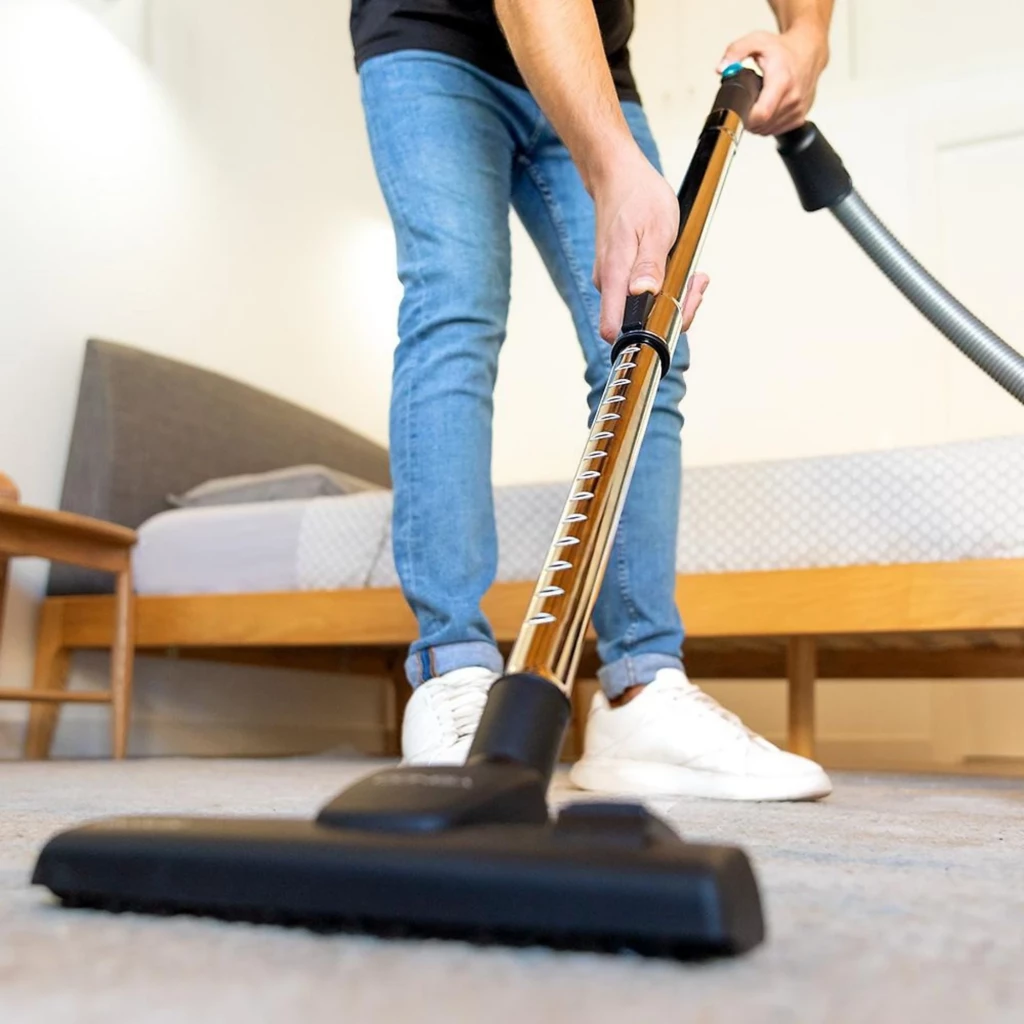 Aspirador de pó com saco preto, corpo compacto com rodas, mangueira flexível, tubo metálico telescópico e bocal largo; inclui acessório estreito para - Item6