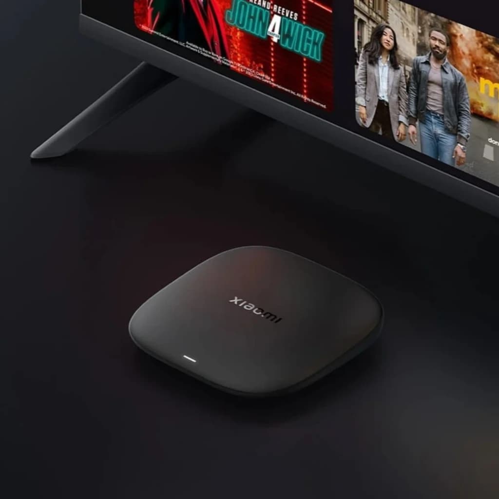 Xiaomi TV Box S 3rd Gen 4K negro mate, diseño compacto cuadrado con bordes redondeados, LED frontal blanco, junto a TV; mando negro con botones de color