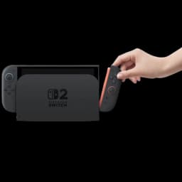 Consola Nintendo Switch 2 en base dock negra con joycon derecho rojo siendo retirado por una mano; pantalla a la izquierda y logotipo 2 en el dock