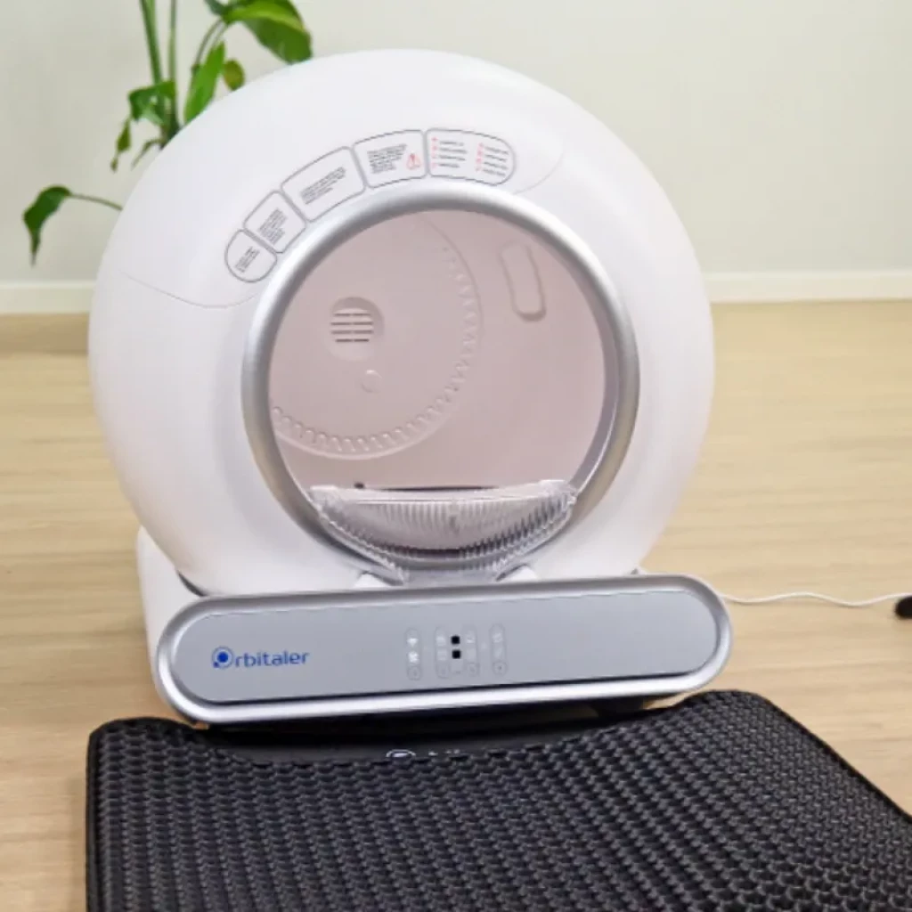Vista frontal do Orbitaler Yupiter AstroClean 6600 Smart Litter Compact, com imagem de um gato e smartphone com aplicação compatível - Item2