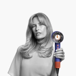 Dyson Supersonic Nural HD16 Ceramic Blue, secador azul con boquilla circular abierta, detalles naranjas, rejilla metálica y cable negro ajustado al mango