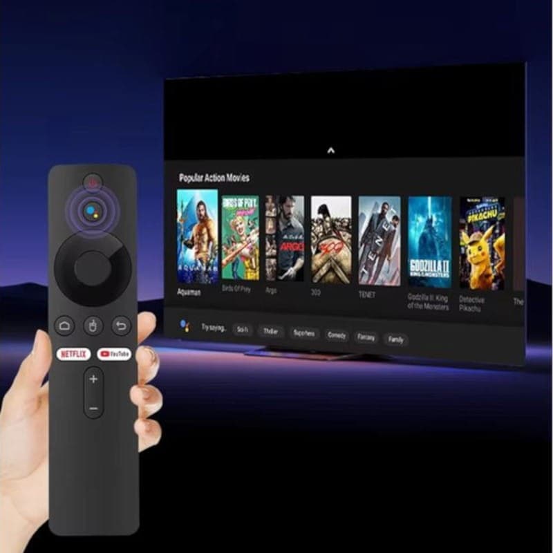 Télécommande noire avec boutons Netflix et YouTube, micro intégré et pavé directionnel, pointée vers un écran affichant interface Android TV et films
