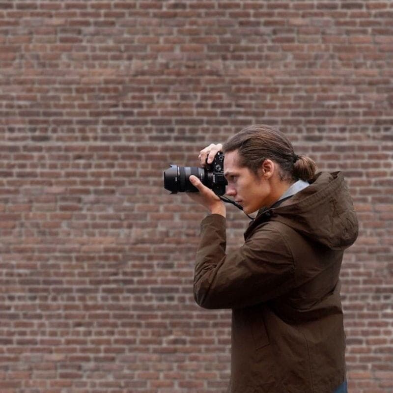 Jeune homme prenant une photo avec l'appareil photo reflex Sony Alpha 7 III Corps MILC Noir