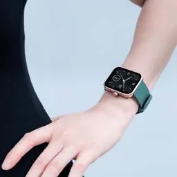Xiaomi Maimo Watch dourado rosa com pulseira verde; caixa quadrada metálica, tela preta com mostrador minimalista e acabamento elegante no pulso
