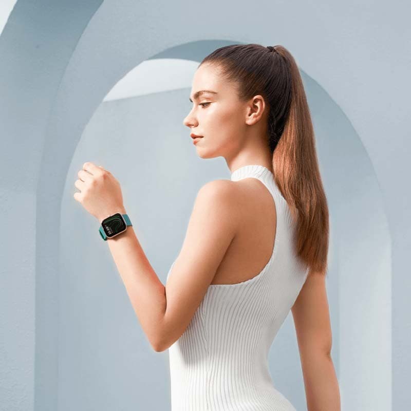 Xiaomi Maimo Watch Dourado Rosa com pulseira verde; caixa metálica dourada, mostrador retangular preto, design elegante no pulso de uma mulher