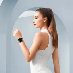 Xiaomi Maimo Watch Dourado Rosa com pulseira verde; caixa metálica dourada, mostrador retangular preto, design elegante no pulso de uma mulher